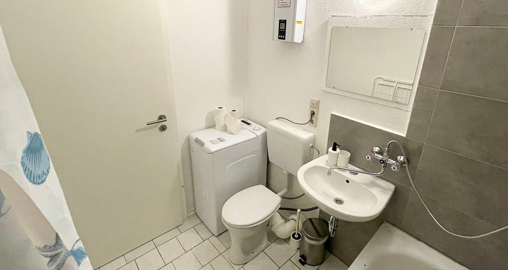 Badezimmer mit Badewanne/Dusche und WC und Waschmaschine
