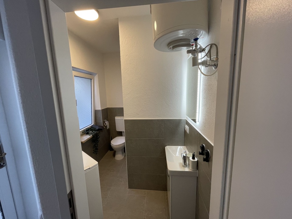 Badezimmer mit Dusche und WC sowie Waschmaschine