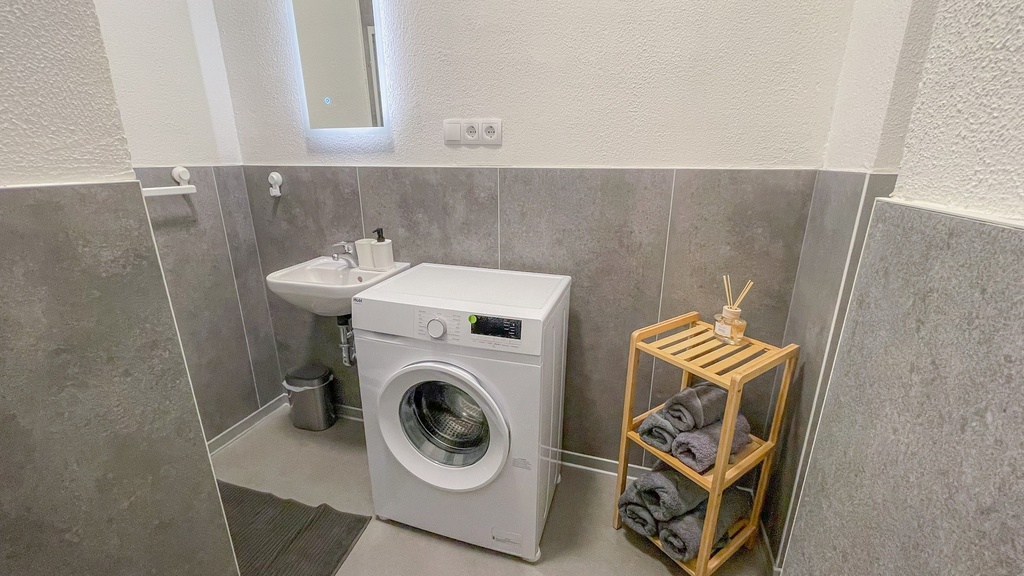 Badezimmer mit Dusche und WC sowie Waschmaschine